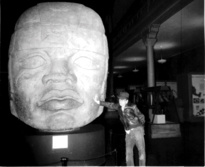 Huey Falk leaning on a giant monolithic face that was evidently worn away over the years.